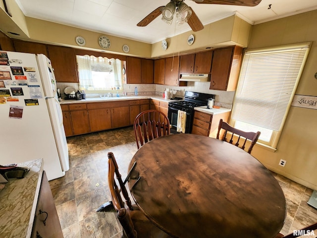 kitchen featuring ceiling fan, crown molding, sink, black gas stove, and white fridge