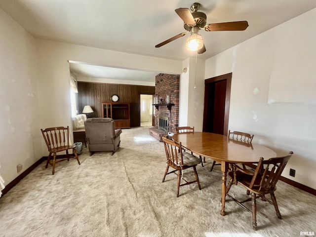 carpeted dining space featuring ceiling fan and a brick fireplace