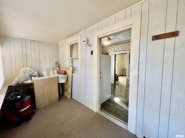 miscellaneous room featuring wooden walls, ceiling fan, and light colored carpet