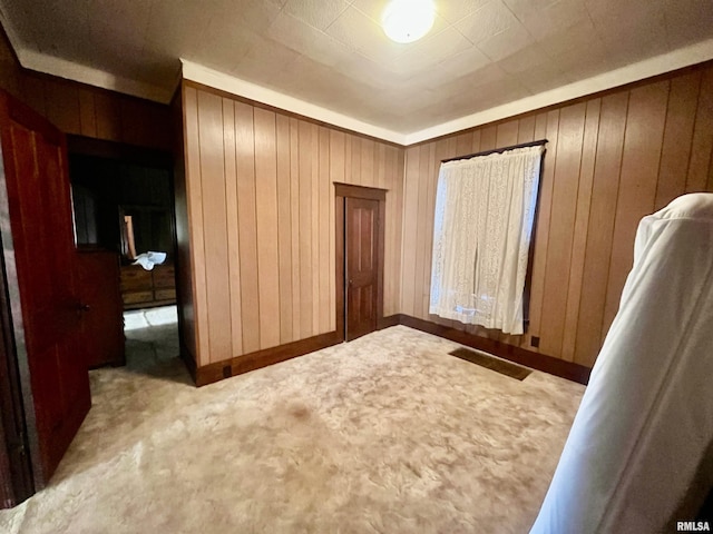 unfurnished bedroom featuring wooden walls and light carpet