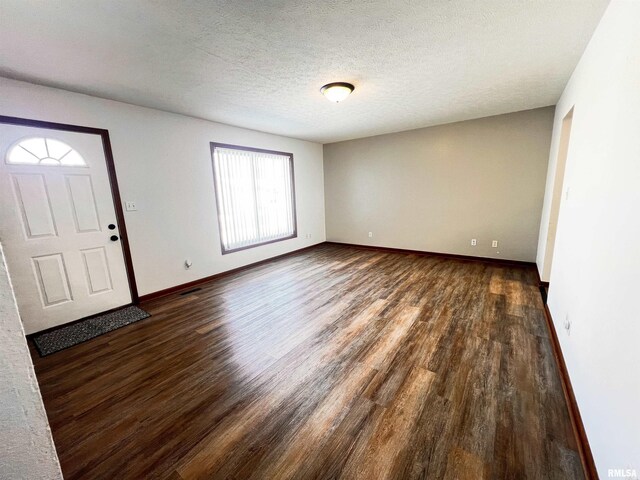 kitchen with a textured ceiling, black fridge, light stone countertops, and wood-type flooring