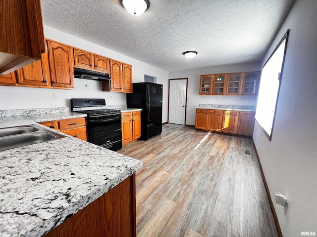 kitchen featuring a textured ceiling, black appliances, and light hardwood / wood-style flooring