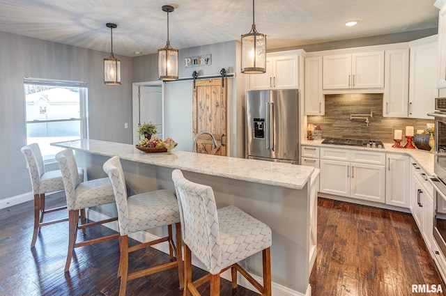 kitchen featuring a center island with sink, decorative light fixtures, high end refrigerator, and a barn door