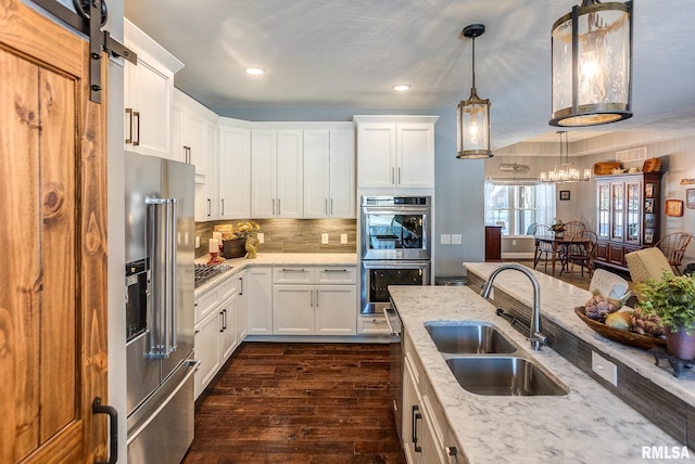 kitchen with stainless steel appliances, white cabinets, hanging light fixtures, and sink