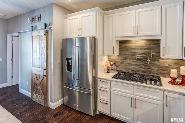 kitchen with light stone countertops, high quality fridge, white cabinetry, gas cooktop, and backsplash