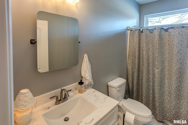 bathroom with curtained shower, vanity, and toilet