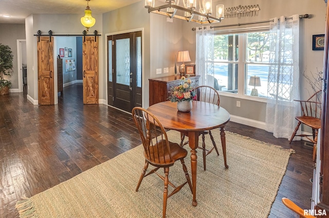 dining area with a notable chandelier, a barn door, and dark hardwood / wood-style floors