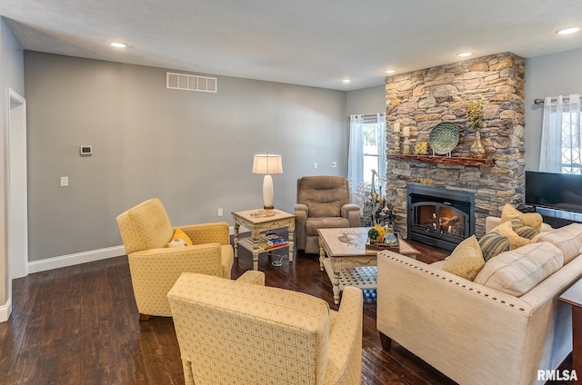 living room featuring dark hardwood / wood-style flooring and a stone fireplace