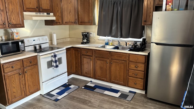 kitchen with appliances with stainless steel finishes, dark hardwood / wood-style flooring, and sink