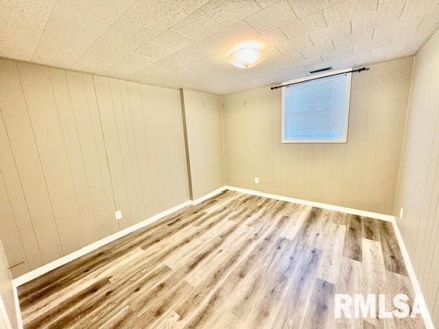 empty room with wood-type flooring and wooden walls