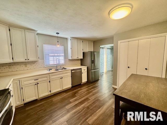 kitchen with hanging light fixtures, white cabinets, sink, and stainless steel appliances