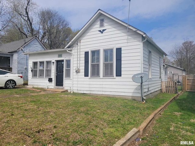 bungalow-style home with fence and a front lawn