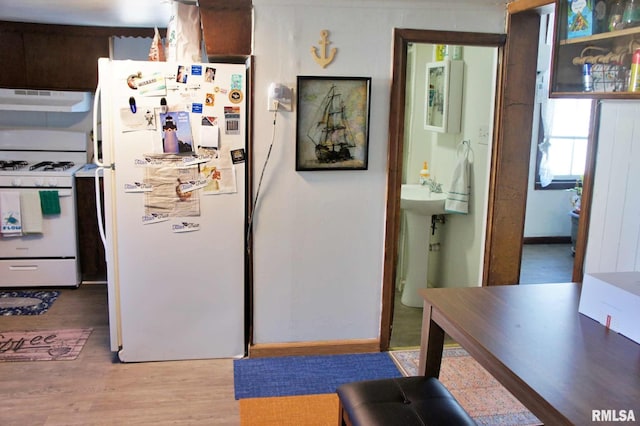 kitchen featuring light wood-type flooring, sink, white appliances, and range hood