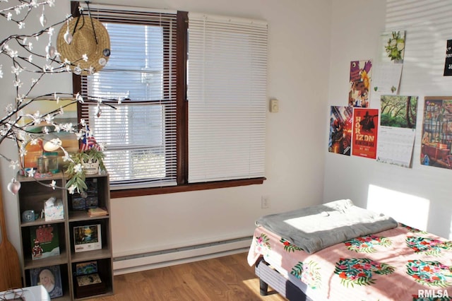 bedroom with wood-type flooring and a baseboard heating unit