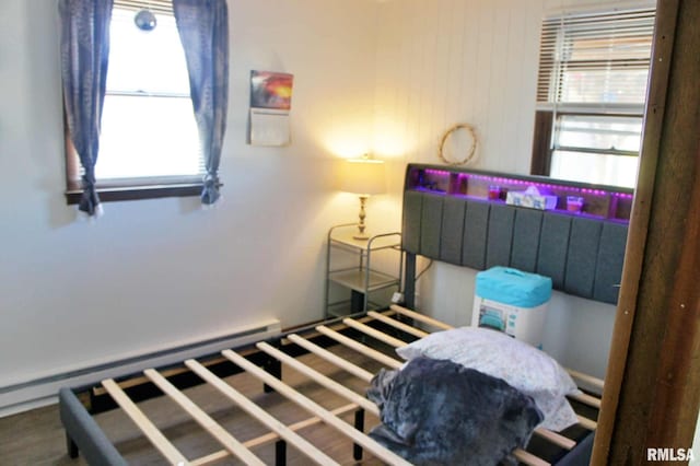 bedroom featuring hardwood / wood-style flooring and a baseboard heating unit