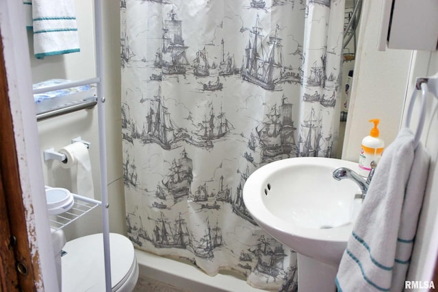 bathroom featuring sink, toilet, and a shower with curtain