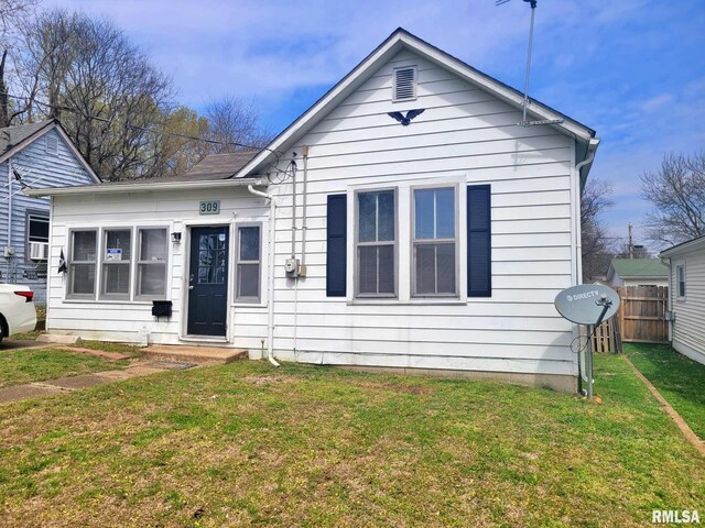 bungalow-style house with a front lawn and fence