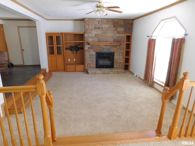 living room featuring a fireplace, ornamental molding, ceiling fan, and carpet