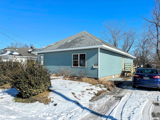 view of snow covered exterior featuring a shingled roof