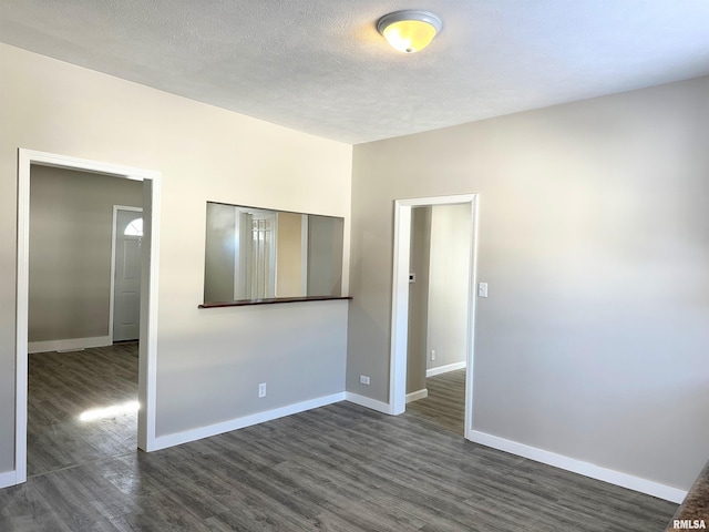 spare room featuring dark wood-type flooring and a textured ceiling