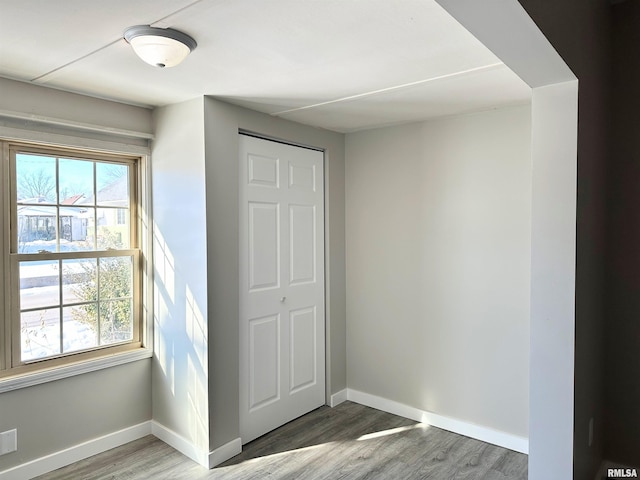 unfurnished bedroom featuring a closet, multiple windows, and wood-type flooring