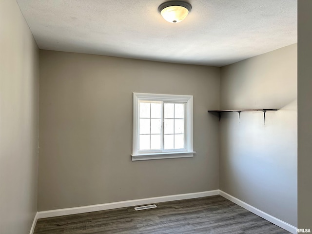 spare room with a textured ceiling and dark hardwood / wood-style floors