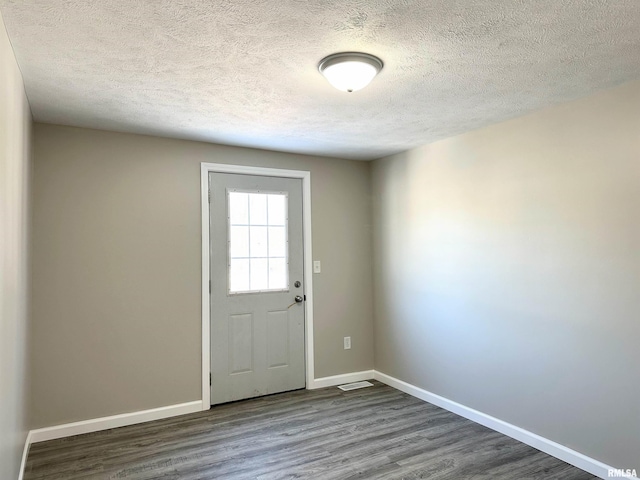 doorway to outside featuring a textured ceiling and dark wood-type flooring