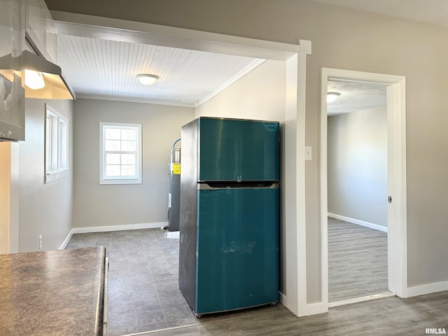 kitchen with fridge, wood-type flooring, ornamental molding, and water heater