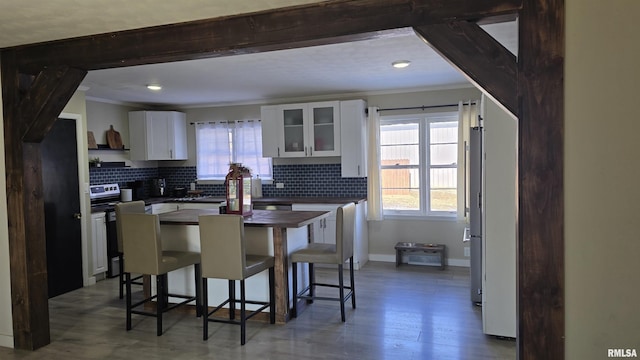 kitchen featuring decorative backsplash, a kitchen breakfast bar, electric range, and white cabinets