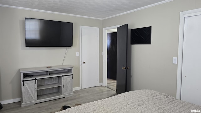 bedroom featuring light hardwood / wood-style flooring, a textured ceiling, and ornamental molding