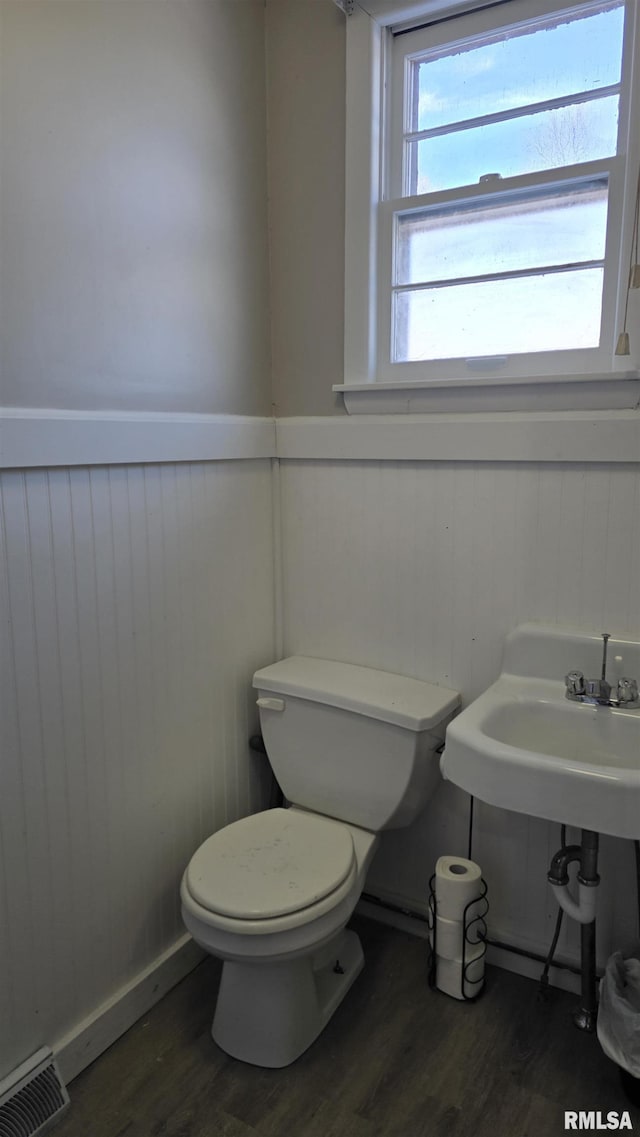 bathroom featuring toilet, wooden walls, and hardwood / wood-style flooring