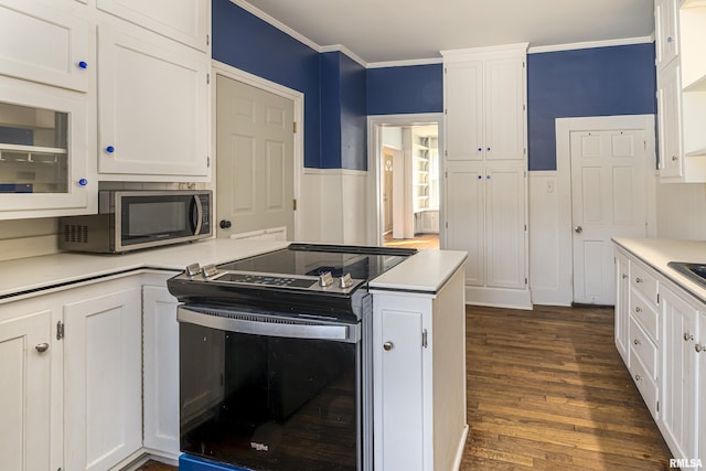 kitchen with white cabinets, dark wood-type flooring, stainless steel appliances, and ornamental molding