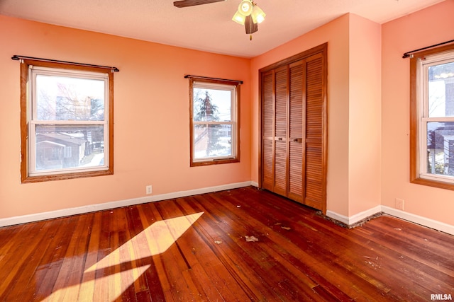 unfurnished bedroom with ceiling fan, dark hardwood / wood-style flooring, and a closet