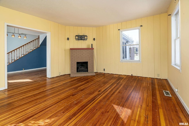 unfurnished living room with a brick fireplace and hardwood / wood-style floors