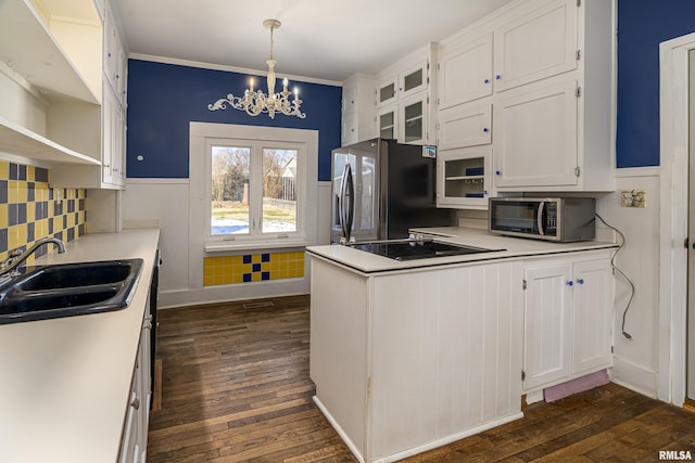 kitchen with sink, an inviting chandelier, hanging light fixtures, stainless steel appliances, and white cabinets