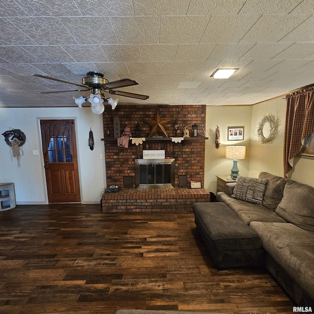 living room featuring dark wood-type flooring, ceiling fan, and a brick fireplace