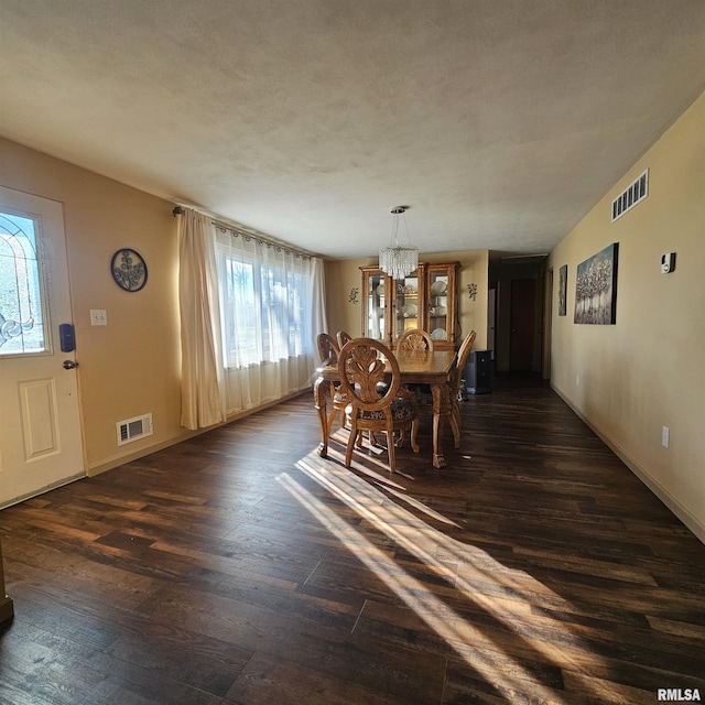 unfurnished dining area featuring dark hardwood / wood-style flooring, a notable chandelier, and a healthy amount of sunlight