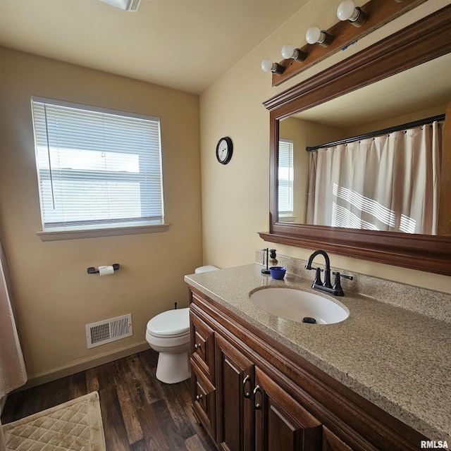 bathroom featuring toilet, vanity, plenty of natural light, and hardwood / wood-style flooring