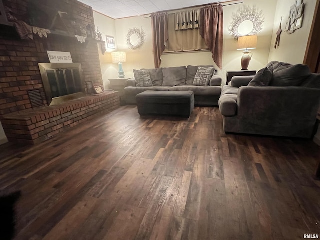 living room with dark wood-type flooring and a brick fireplace