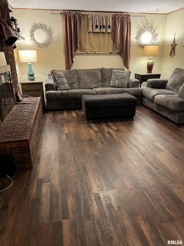 living room featuring dark wood-type flooring, crown molding, and a fireplace