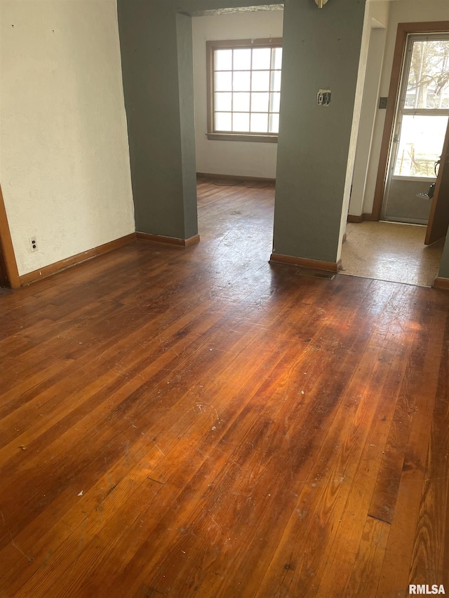 empty room with baseboards, wood-type flooring, and plenty of natural light