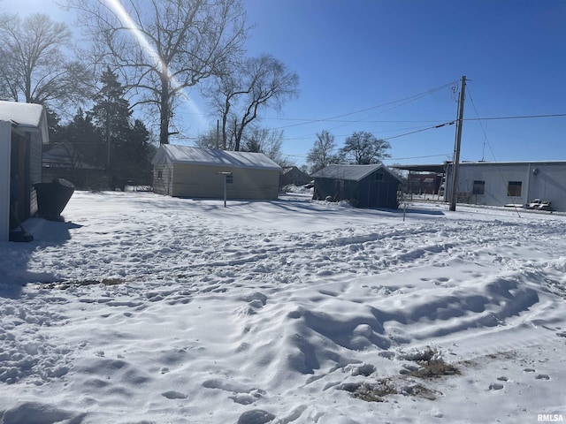 snowy yard featuring an outbuilding and a shed