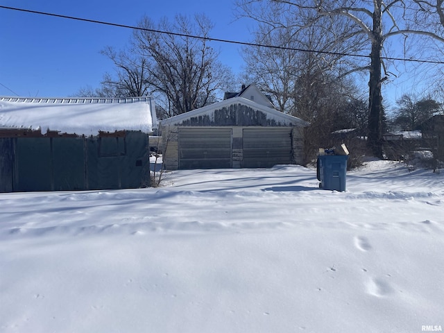 yard layered in snow featuring a garage and an outdoor structure