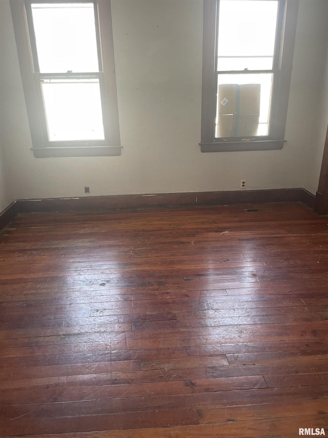 spare room featuring baseboards and dark wood-style floors