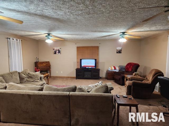 carpeted living room featuring a textured ceiling and ceiling fan