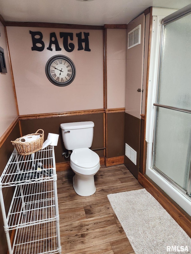 bathroom featuring toilet, a shower with door, and hardwood / wood-style flooring