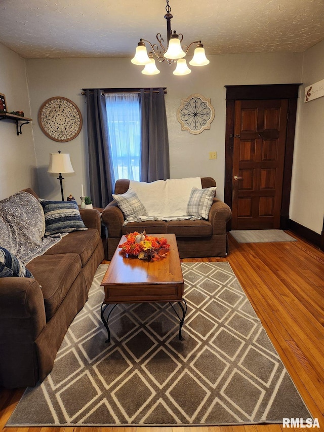 living room featuring hardwood / wood-style flooring, a textured ceiling, and an inviting chandelier