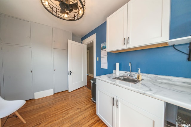 clothes washing area with sink and light hardwood / wood-style floors