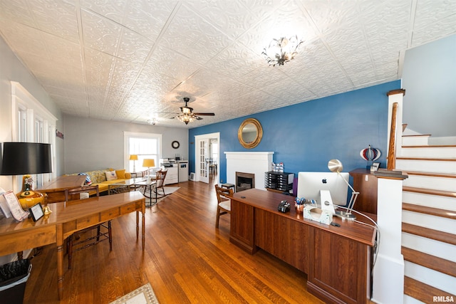 home office with french doors, ceiling fan with notable chandelier, and wood-type flooring