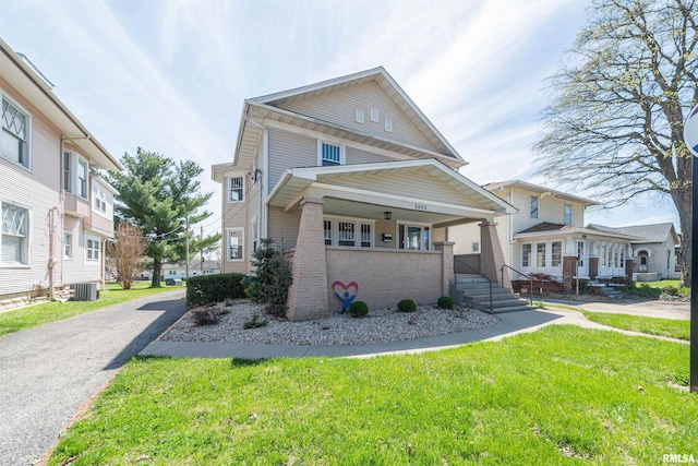 view of front of home with covered porch, a front lawn, and central AC